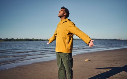 En mand i en gul jakke står på en strand