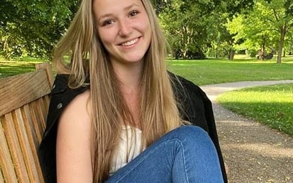 Jule Bohe draußen in einem Park auf einer Bank sitzend 