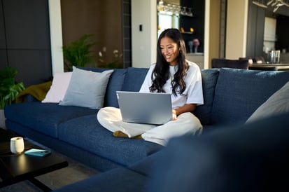 Vrouw zit op de bank met haar laptop