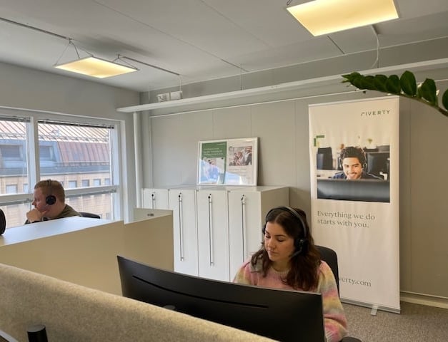 A picture of Thelma and her colleague working at their deck in the office