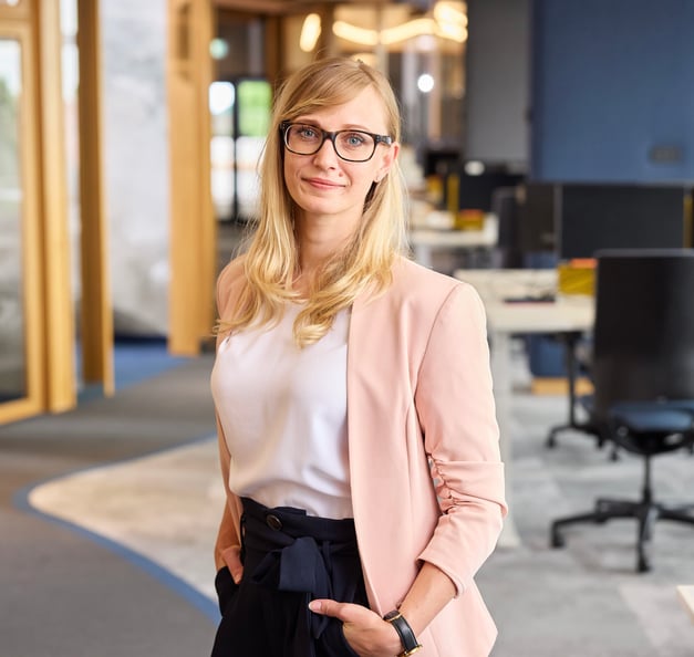 Das Bild zeigt Regina stehend im Büro, die Hände in den Hosentaschen.