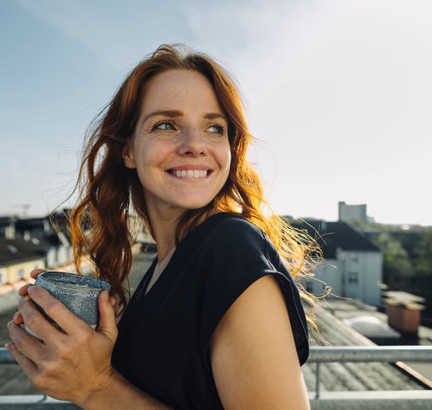 woman smiling and holding a cup 