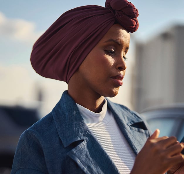 Frau, die sich in der Stadt befindet und auf ihr Smartphone blickt.