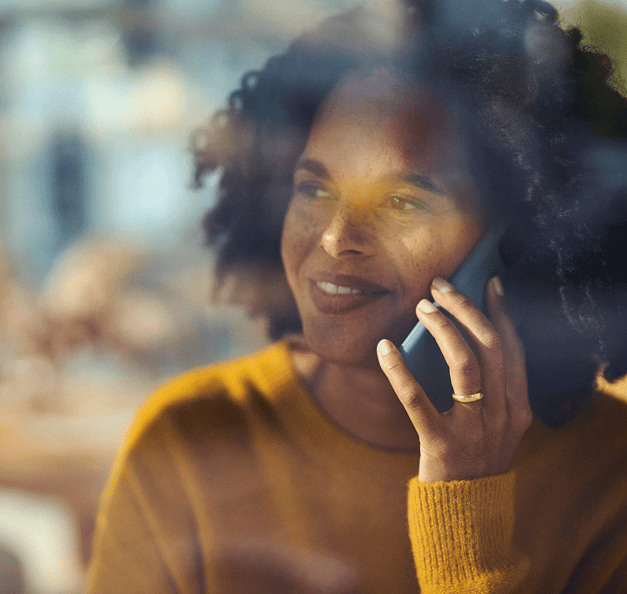 hymyilevä nainen puhuu puhelimessa