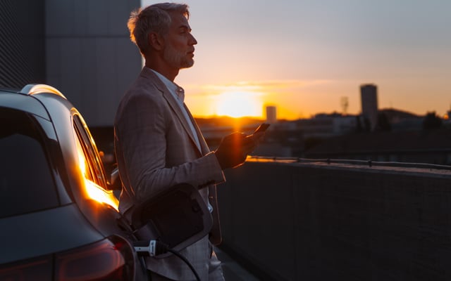 A man charges his EV automobile