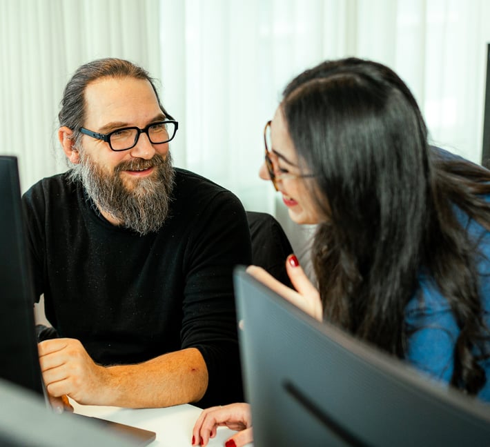 two riverty colleagues working in the office, talking and laughing
