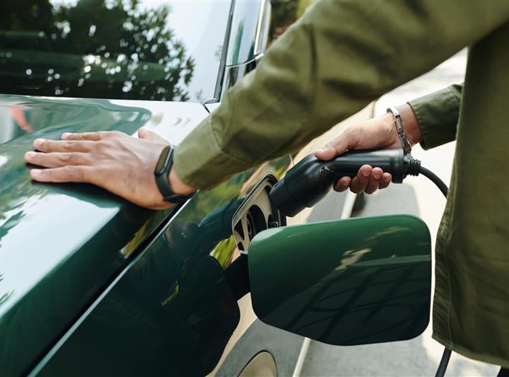 Green, electric vehicle being plugged into a charging station
