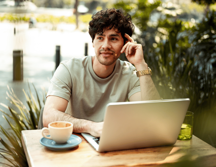 Een man zit buiten achter zijn laptop na te denken