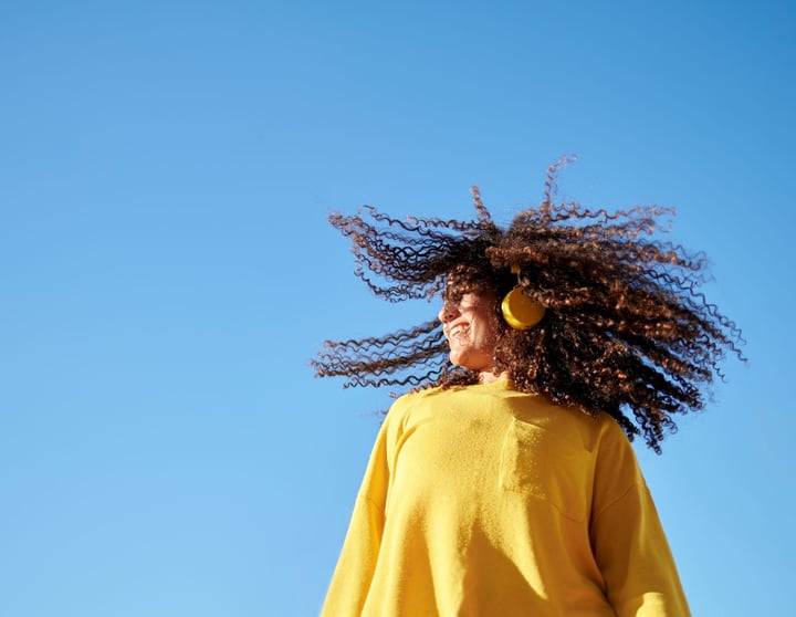 Een gelukkige jonge vrouw danst met gele koptelefoon op een mooie winterdag
