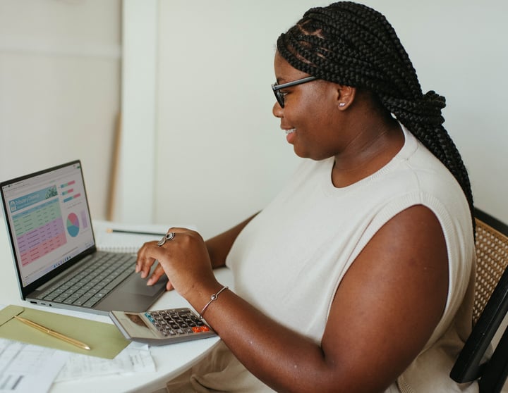Eine junge Frau sitzt am Tisch und tippt auf ihrem Laptop