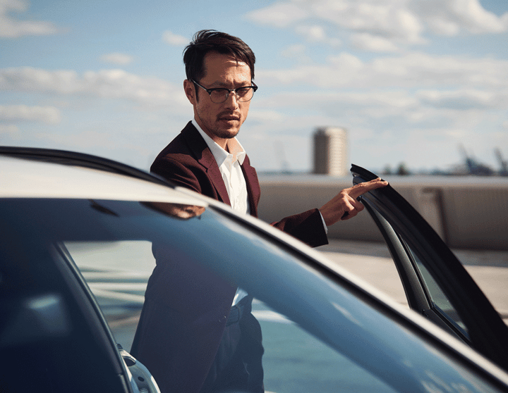 A man with glasses standing next to a car