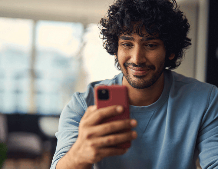 Mens die bij zijn telefoon glimlacht
