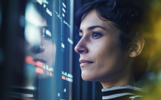 Eine Frau, die auf einen Computerbildschirm blickt, mit sichtbaren Datenreflexionen.