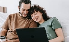 happy couple sitting infront of a laptop