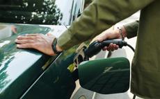 Green, electric vehicle being plugged into a charging station