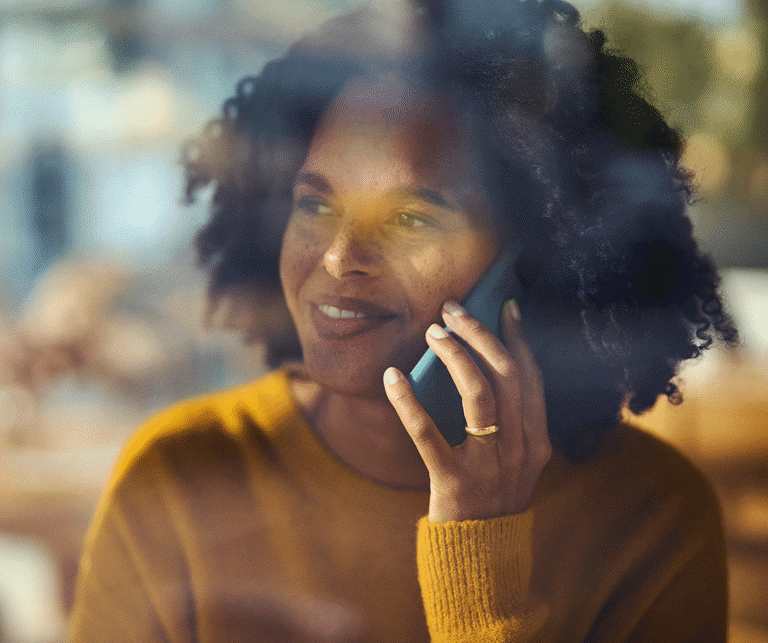 Kvinde med gul sweater taler i mobiltelefon