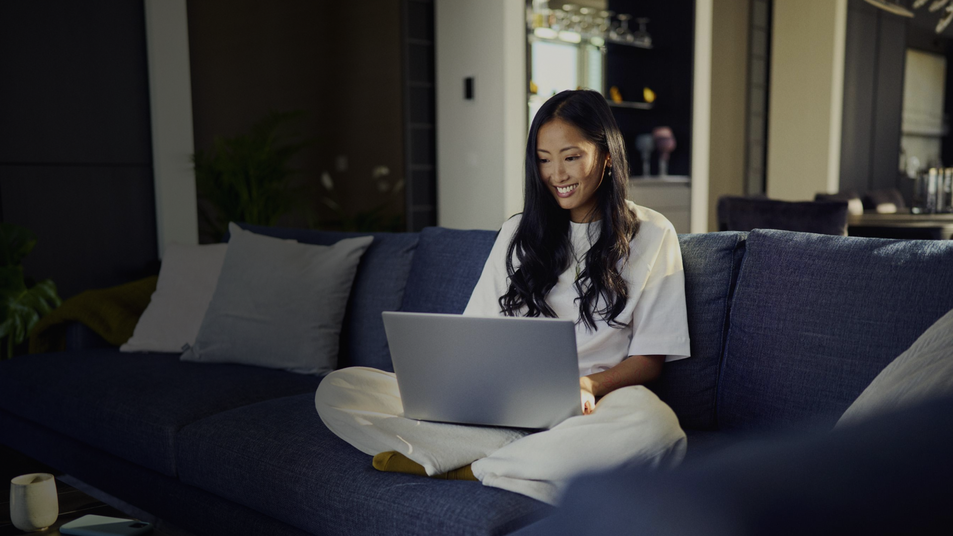 Woman in her home, sitting on a couch shopping online and using Riverty Pay in 3