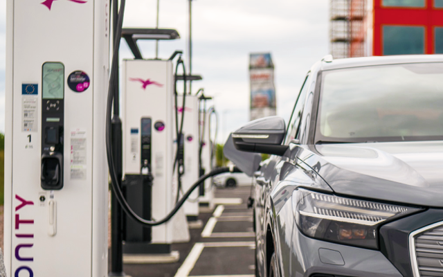 Electric car charges at Ionity station with cable plugged in.
