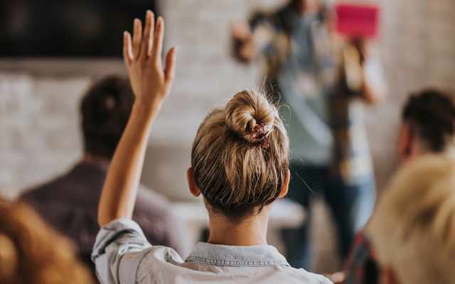 Een mevrouw steekt haar hand op