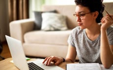 Eine junge Frau sitzt an ihrem Laptop und sucht nach Informationen zum Thema Insolvenzverfahren.