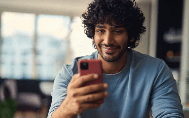 Mens die bij zijn telefoon glimlacht