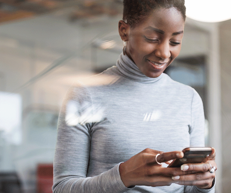 Frau in einem modernen Büro, die ihr Smartphone ansieht