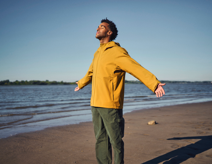 En mand i en gul jakke står på en strand