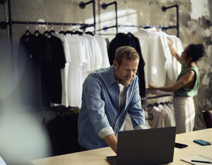 En mand står ved en laptop i en tøjbutik