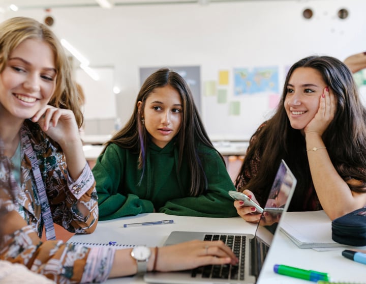 eine Gruppe von Schülerinnen, die vor ihren Schulbüchern sitzt
