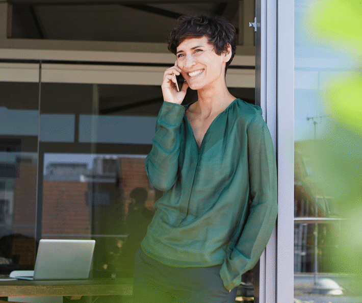 En kvinde i en mørkegrøn skjorte taler i mobiltelefon