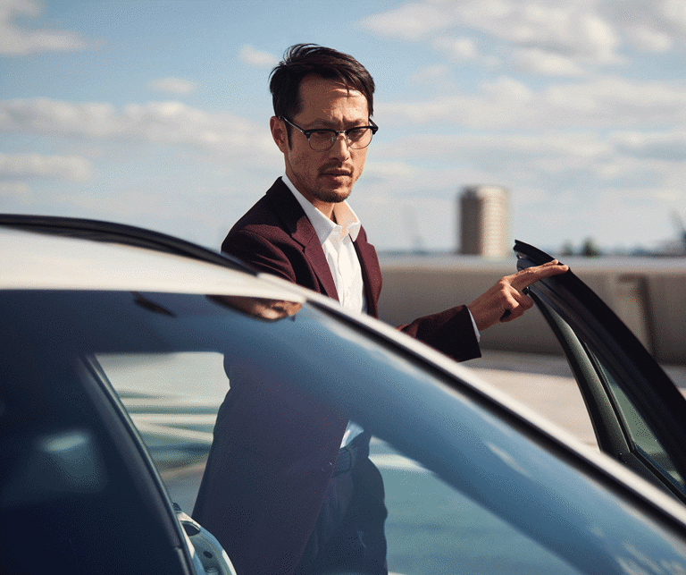 A man is standing next to his car 