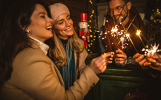 Eine Freundesgruppe steht draußen und feiert mit Sekt und Wunderkerzen in das neue Jahr