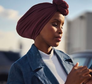 Gefocuste vrouw met een hoofddoek, staat buiten en gebruikt haar smartphone voor digitale betalingen.