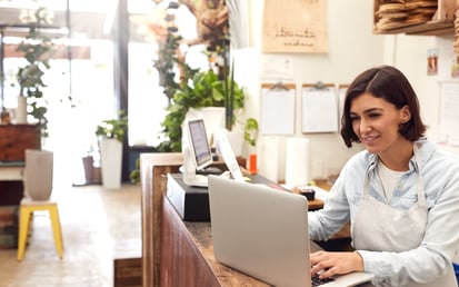 A women is standing next to her laptop smiling