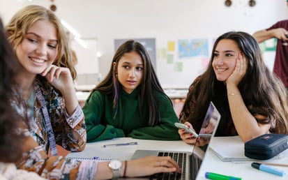 eine Gruppe von Schülerinnen, die vor ihren Schulbüchern sitzt